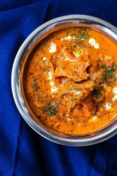 a metal bowl filled with food on top of a blue cloth