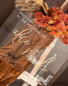 a welcome sign with flowers and feathers hanging from it's front window for guests to see