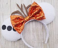 a close up of a minnie mouse head with orange sequins and a bow