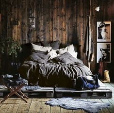 an unmade bed in a rustic bedroom with wood paneled walls and flooring