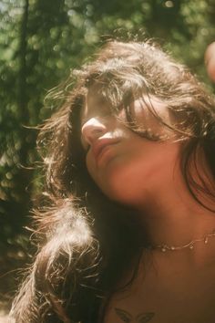 a woman with long brown hair and tattoos on her chest