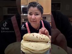 a woman holding a stack of food in front of her face and making a funny face