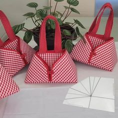 three red and white bags sitting on top of a table next to a potted plant