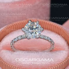 an engagement ring with diamonds on display in a pink velvet box, close up view