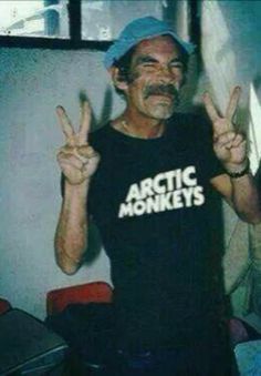 an old man is making the peace sign with his hands and wearing a t - shirt that says arctic monkeys