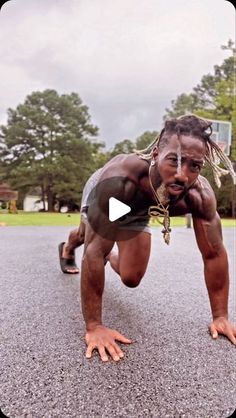 a man with dreadlocks is doing a push up on his skateboard in the street