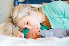 a woman laying on top of a bed next to a baby