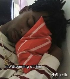 a man with dreadlocks is sleeping on a bed wearing a red and white striped shirt