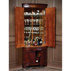 a wooden cabinet with wine glasses and liquor bottles in the bottom section, on display