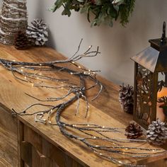 a wooden table topped with lots of pine cones and branches next to a candle holder