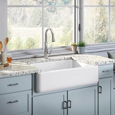 a white kitchen sink sitting under a window next to a counter top with utensils