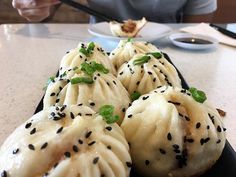 some dumplings with black sesame seeds on them are sitting on a plate at a table