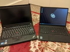 two laptops side by side on a rug