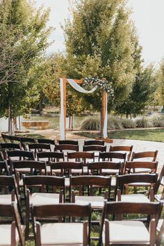 an outdoor ceremony set up with wooden chairs