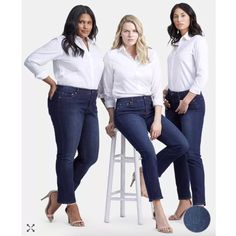 three women standing next to each other in front of a white background and one is sitting on a stool