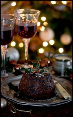 a table with two glasses of wine and a cake on the plate next to it