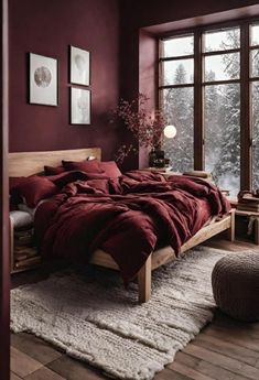 a large bed sitting in a bedroom next to a window covered in red sheets and blankets