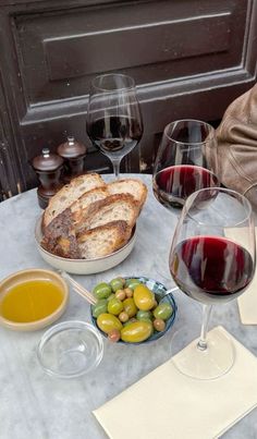 a table topped with glasses of wine, bread and olives on top of it