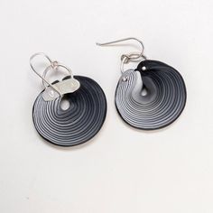 pair of black and white circular earrings with metal hooks hanging from the ends, on a white background