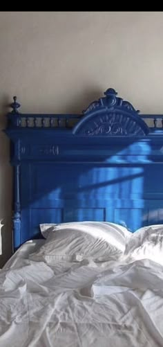 a bed with white sheets and blue headboard