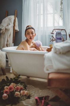 a woman sitting in a bathtub holding a stuffed animal