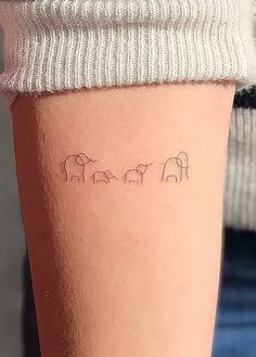 three elephants tattoo on the left side of the calf's leg, which is written in cursive writing