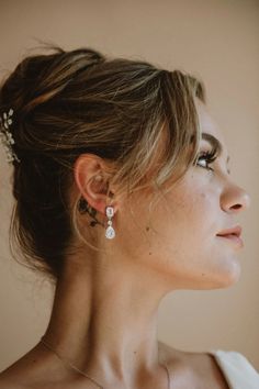 a woman in a white dress is wearing some kind of earring with pearls on it