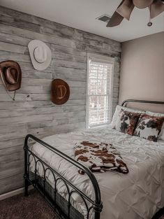 a bed in a bedroom with two hats on the wall above it and a ceiling fan