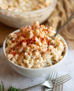 a bowl filled with macaroni salad next to a fork