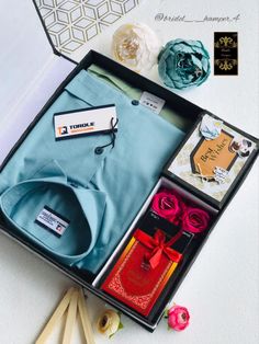 an open box with clothes and flowers on the table