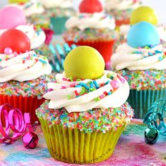 colorful cupcakes with white frosting and sprinkles on a table