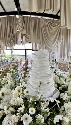 a large white wedding cake sitting on top of a table covered in lots of flowers