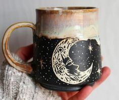 a hand holding a coffee mug with a moon and stars painted on the inside of it