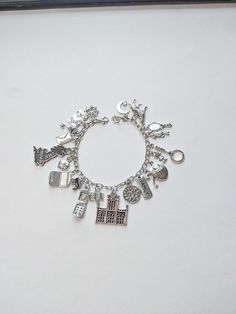 a silver bracelet with charms on it sitting on top of a white table next to a clock