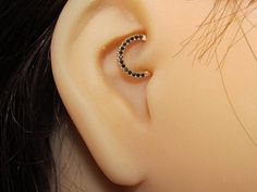 a close up of a person's ear with a black and white diamond ring on it