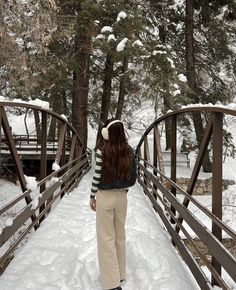 a woman standing on a bridge in the snow with her back turned to the camera