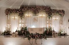 a decorated stage with flowers and greenery on the wall for a wedding ceremony or reception