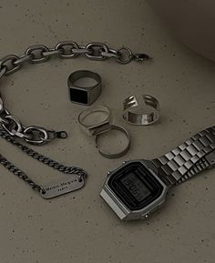 a watch, chain, and other items are laying on the table together in this image