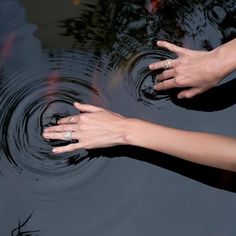 two hands touching each other in the water with their fingers extended out to touch them