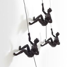 three black figurines hanging from ropes on the wall