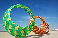 two large colorful kites sitting on top of a sandy beach