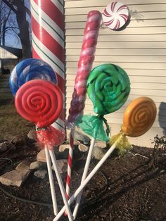 some lollipops are sitting in the dirt near a building with candy canes