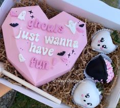 there is a heart shaped cake in the box with other treats on it, including marshmallows and strawberries