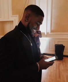 a man in a black jacket looking at his cell phone while standing next to a table