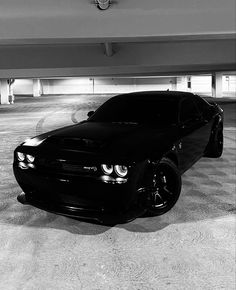 a black and white photo of a car parked in a parking garage with its lights on