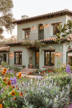 a large house with lots of flowers in the front yard and stairs leading up to it