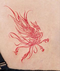 a red ink drawing of a bird on the back of a woman's shoulder