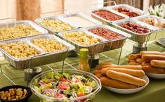 hot dogs, salads and other foods are displayed on a table at a party