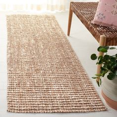 a rug on the floor next to a chair and potted plant in front of a window