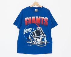 a t - shirt with the giants helmet on it is hanging on a hanger